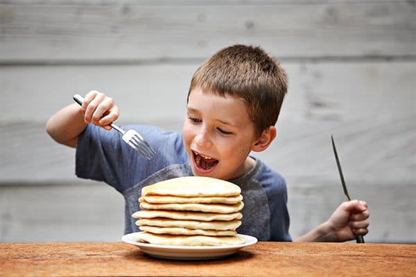 boy eating pancakes happily