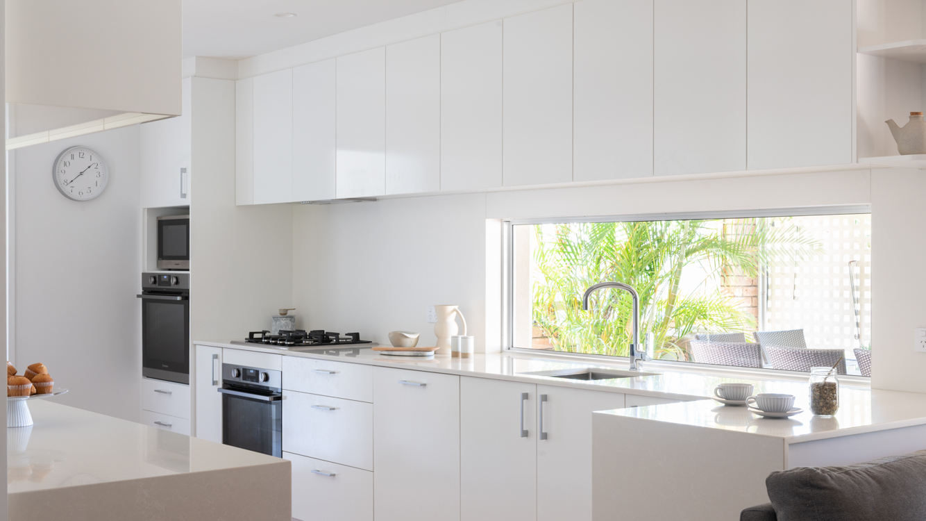 Caesarstone Benchtops 7 Caesarstone Alpine Mist benchtop with a waterfall end, white drawers and tall cabinetry around the fridge in a Willetton kitchen