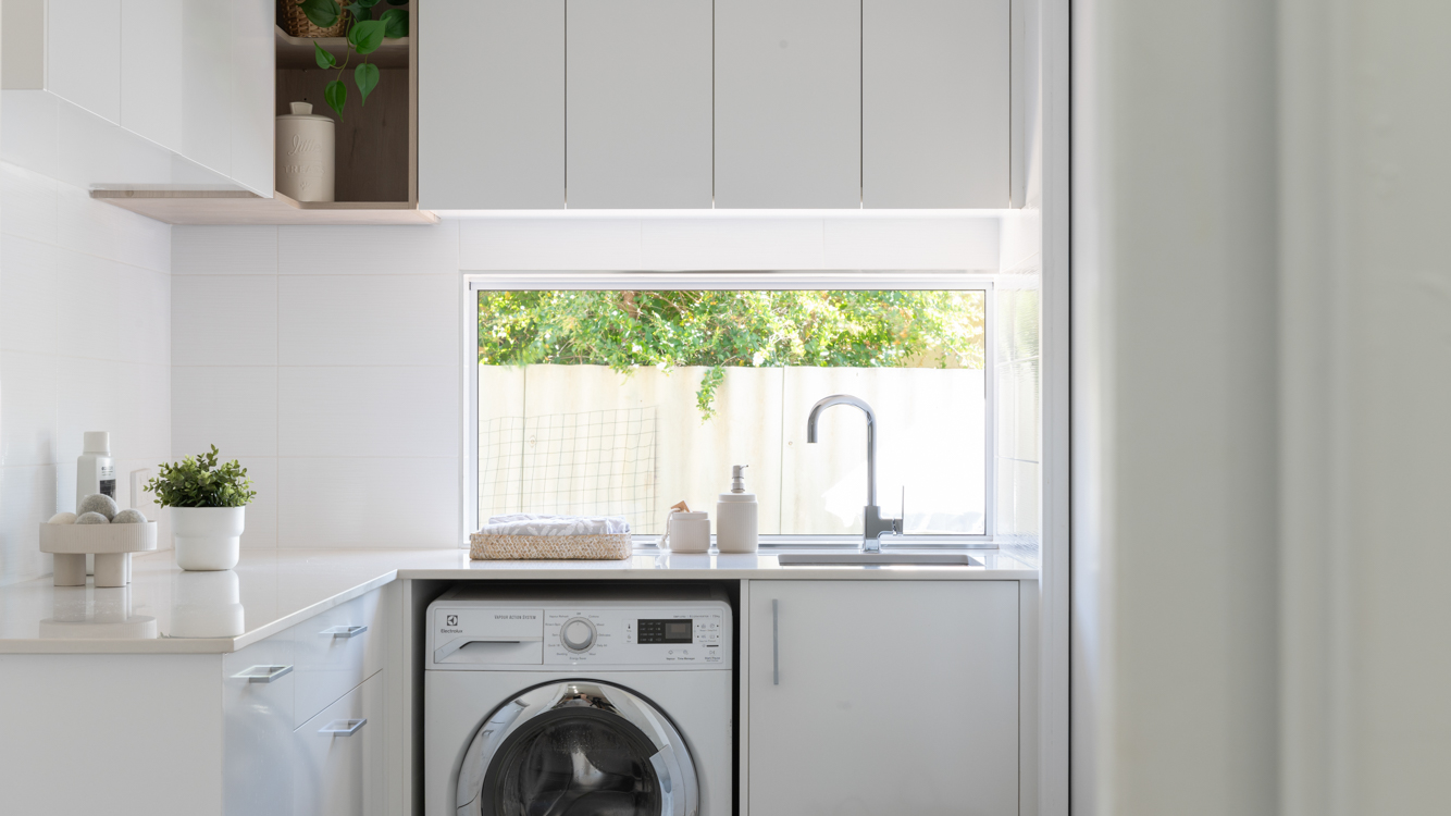 Caesarstone Benchtops 8 Willetton laundry with a Caesarstone Alpine Mist benchtop, white cabinetry and a window splashback above the sink