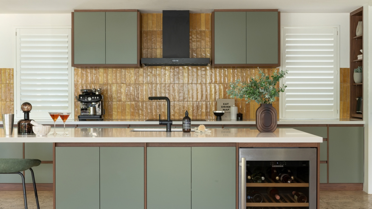 Caesarstone Benchtops 12 Caesarstone Osprey benchtops with sage green cabinetry, an amber tile splashback and a black rangehood in a North Coogee kitchen