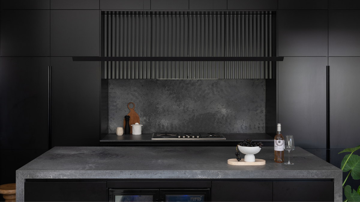 Caesarstone Benchtops 9 Karrinyup kitchen with floor to ceiling black cabinetry, a Caesarstone Rugged Concrete waterfall island and a built in wine fridge