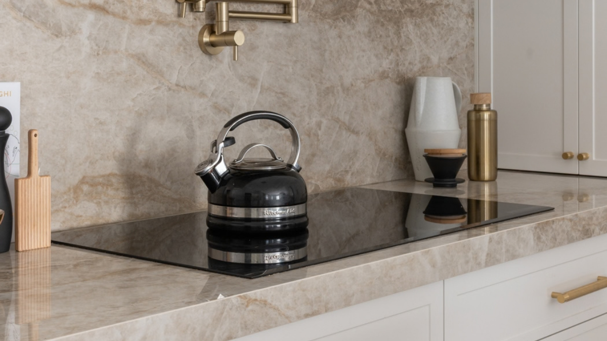 Dekton Benchtops 6 Dekton Taga splashback with a brass pot filler above an induction cooktop and white shaker cabinetry in an Alkimos kitchen
